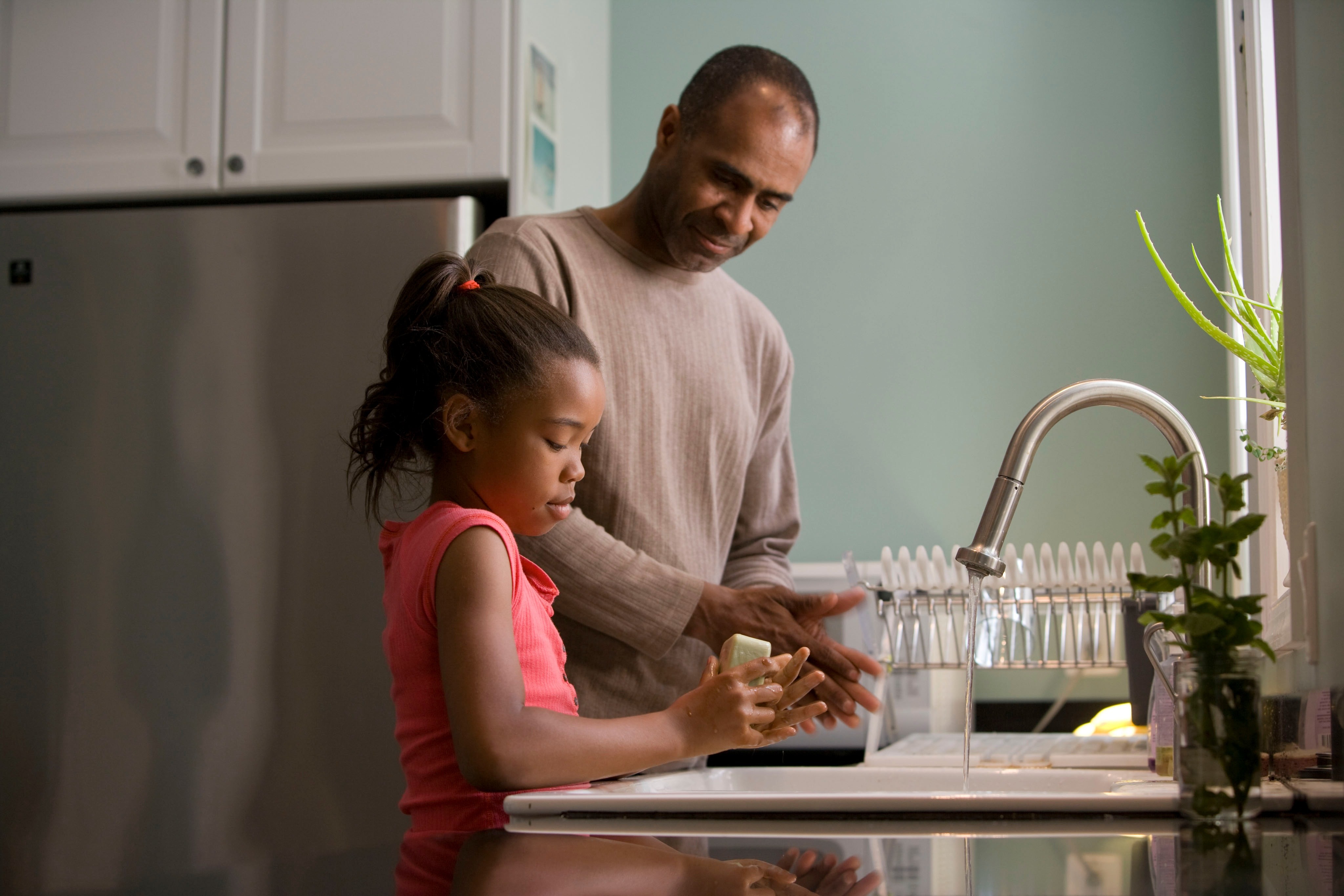Photo of a dad and daughter, washing their hands in the kitchen